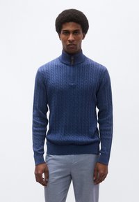 Πλεκτό πουλόβερ σε ναυτικό μπλε με ψηλό γιακά, διαθέτει φερμουάρ στο χρώμα αντίθεσης στο ένα τέταρτο του μήκους και ριμπ μανσέτες και τελείωμα.