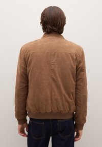 Braune Wildleder-Bomberjacke mit gerippten Bündchen und Taillenbund, zeichnet sich durch eine glatte Textur und schlichtes Design aus. Rückansicht zeigt Nahtdetails.