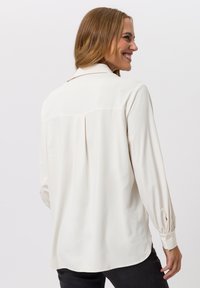 Witte blouse met lange mouwen, een kraag, een plooi aan de achterkant en manchetten met knopen, gemaakt van een glad, lichtgewicht stof.