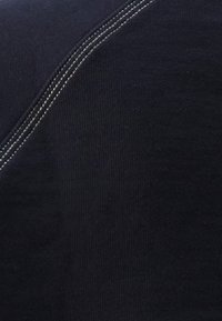 Tejido azul marino con textura acanalada; presenta costuras de contraste en un tono claro; la vista en primer plano resalta el detalle y la suavidad.