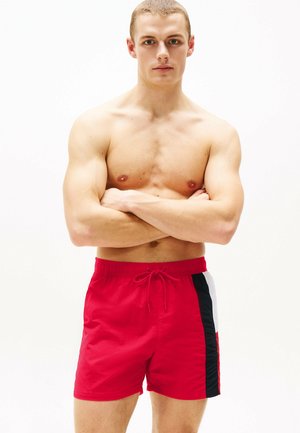 Rote Badeshorts mit elastischem Bund und Kordelzug, ausgestattet mit schwarzen und weißen Seiteneinsätzen. Glattes, leichtes Material.