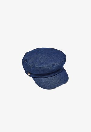 Casquette de pêcheur en denim bleu avec une visière courte et un détail en bouton argenté sur le côté, présentée sur un fond blanc.