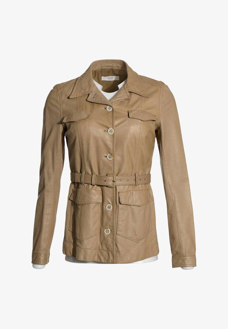 Veste en cuir beige avec boutons à l’avant, taille ceinturée, quatre poches à rabat et col classique sur une chemise blanche.