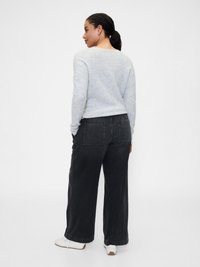 Suéter de punto gris y jeans de pierna ancha negros. El suéter tiene un escote redondo y los jeans cuentan con bolsillos traseros. Zapatillas blancas completan el conjunto.