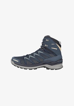 Knöchelhoher Wanderschuh in Marineblau, ausgestattet mit einem Mesh-Obermaterial, Gummisohle und Schnürdesign. Reflektierende Akzente und wasserdichtes Gore-Tex-Material.