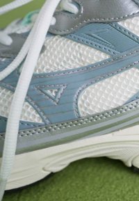 Lightweight athletic shoe featuring a breathable white mesh upper with blue and silver accents, textured detailing, and white laces.