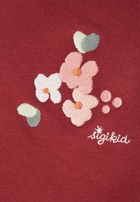 Roter Stoff mit gestickten Blumen in Rosa- und Weißtönen, grünen Blättern und einem kleinen orangefarbenen Zentrum, mit dem Aufdruck "sigikid".