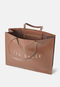 Sac fourre-tout marron Ted Baker London avec deux poignées, ouverture sur le dessus et poche intérieure zippée visible.