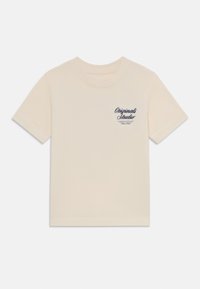 Cream-colored short-sleeve t-shirt made from soft cotton. Features a small navy printed logo on the left chest.