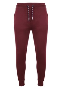 Burgundské joggingové kalhoty vyrobené z měkké látky, disponující elastickým pasem s šňůrkou a přiléhavými manžetami u kotníků.