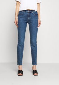 Smal blå jeans av denim med en klassisk femficksdesign. De har en lätt blekning fram och hög midja.