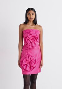 Stroppeløs rosa kjole med store stoffblomst dekorer på bysten og skjørtet, med en glatt tekstur og figursydd silhuett.
