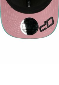 Rosa Kappe mit schwarzem Schirm und mintgrünen Akzenten. Verfügt über ein großes schwarzes Logo und ein reflektierendes Etikett auf dem Schirm. Die Naht ist auffällig.