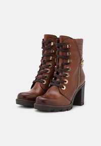 Bottines en cuir marron avec un laçage sur l'avant, des détails en métal doré, une fermeture éclair sur le côté et un large talon noir ; finition texturée.