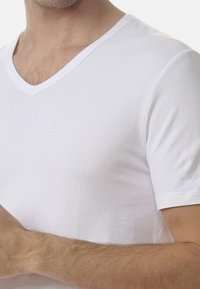 Vit t-shirt med v-hals i mjukt tyg, kortärmad, figurnära design med en slät yta och rena sömmar.