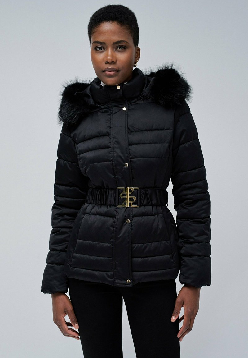 Chaqueta tipo puffer negra con cierre de cremallera y broche, con capucha de piel sintética, cintura elástica con hebilla en tono dorado y textura acolchada.