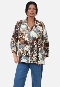 Floral button-up shirt featuring a mix of brown, cream, and blue colors, with a loose fit and three-quarter sleeves, made from lightweight fabric.