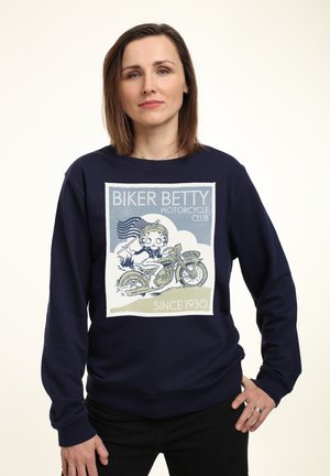 Marin sweatshirt med et hvidt grafisk design af en karakter på en motorcykel, med teksten "Biker Betty Motorcycle Club" og "Since 1930".