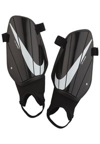 Espinilleras Nike negras que cuentan con una carcasa suave y protectora con acentos y estrías en blanco, aseguradas con correas de tela para mayor comodidad.