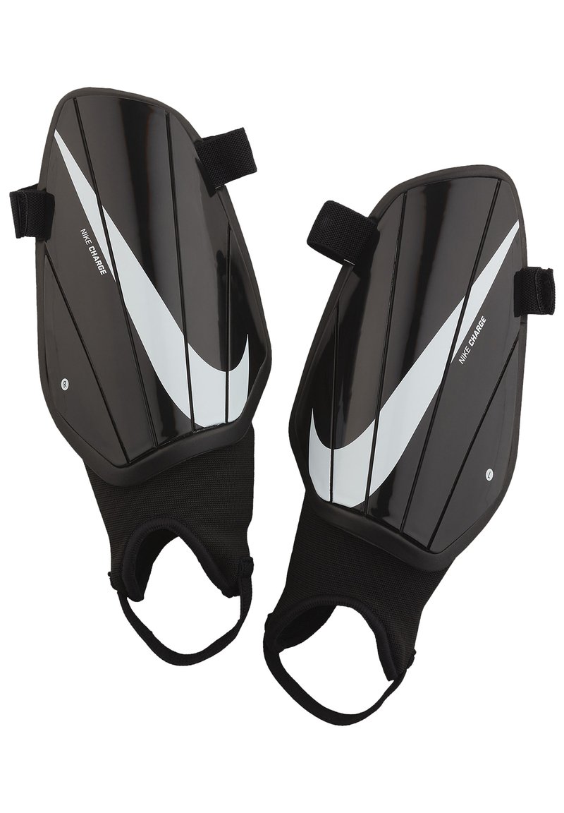 Espinilleras Nike negras que cuentan con una carcasa suave y protectora con acentos y estrías en blanco, aseguradas con correas de tela para mayor comodidad.