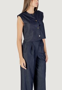 Top smanicato in denim scuro con scollatura rotonda e chiusura anteriore a bottoni, abbinato a pantaloni a gamba larga coordinati. Texture liscia e design aderente.