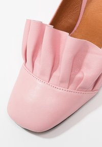 Chaussure plate en cuir rose doux avec un bout carré et des détails froncés sur la tige, avec une doublure intérieure couleur cuir naturel.