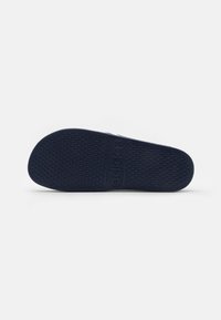 Mørkeblå gummisåle med et teksturert diamantmønster. Logoen "adidas" er tydelig preget nær midten.