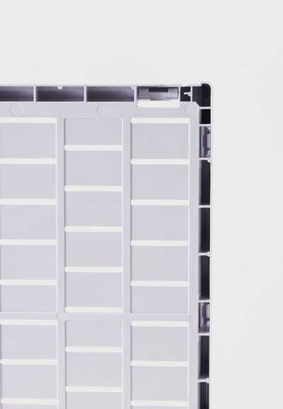 Κοντινή λήψη ενός γκρι πλαστικού παλετοκιβωτίου με ορθογώνια τμήματα πλέγματος και ενισχυμένες άκρες σε λευκό φόντο.