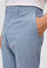 Helleblau, strukturierten Hosen mit tailliertem Schnitt, ausgestattet mit Seitentaschen und flachem Vorderteil. Der Stoff hat ein dezentes Webmuster.