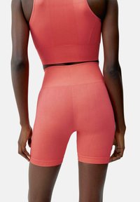 Röd stretchig sport-bh och högmidjade shorts. Texturerad yta med ribbad detalj. Följsam design.