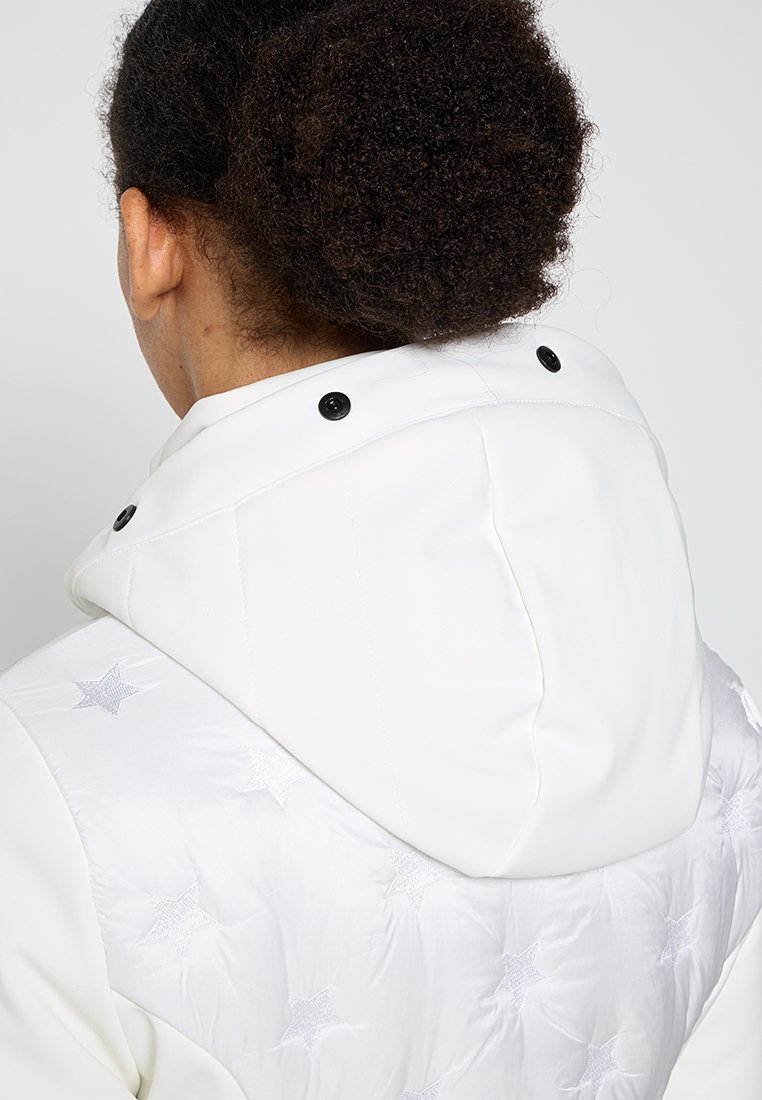 Giacca bianca con cappuccio caratterizzata da un design trapuntato con motivi di stelle argentate e dettagli con bottoni sul cappuccio. Tessuto uniforme con un taglio moderno.
