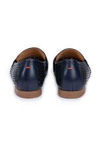 Scarpe slip-on in pelle blu navy con design perforato, suola in gomma color tan e piccolo accento rosso sul tallone. Presenta superficie liscia e strutturata.