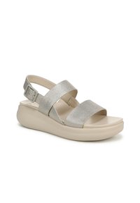 Sandalo con suola piatta beige, cinturini texturizzati argento metallico, fibbia alla caviglia regolabile e design open-toe per una maggiore traspirabilità.