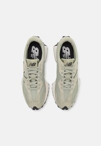Light green athletic shoes made of mesh and suede, featuring a black and white sole, round laces, and recognizable logo on the tongue.