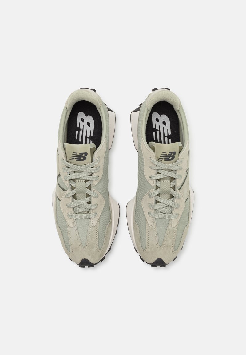 Hellgrüne Sportlichschuhe aus Mesh und Wildleder, mit einer schwarz-weißen Sohle, runden Schnürsenkeln und einem auffälligen Logo auf der Zunge.