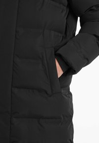 Black puffer coat with a smooth texture, featuring a vertical seam, side pockets, and a fold-over collar.
