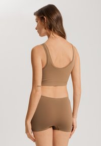 Top sin mangas de tela suave marrón con tirantes anchos y pantalones cortos a juego. El diseño presenta un acabado sin costuras y un ajuste ceñido y cómodo.