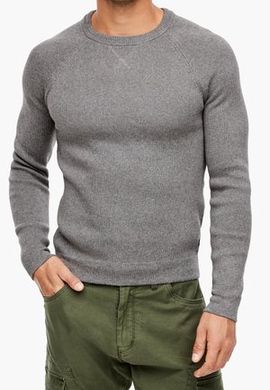 Pull en maille grise avec un col ras du cou et des poignets côtelés. Caractéristiques d'un tissu texturé avec une coupe ajustée, associé à un pantalon cargo vert olive.