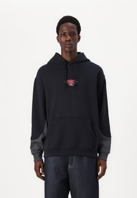 Hoodie noir avec une poche avant, cordon ajustable et accents gris sur les manches. Présente un petit logo rouge sur la poitrine.