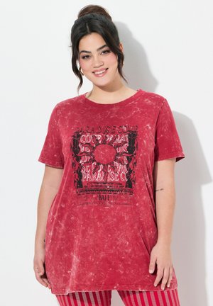 Červené oversized tričko vyrobené z organické bavlny s efektem tie-dye, s černým grafickým potiskem ve středu a krátkými rukávy.