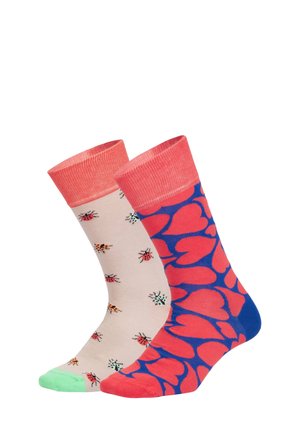 Zwei bunte Socken: eine beige mit mehrfarbigen Marienkäfern und korallenfarbener Bündchen, die andere blau mit großen korallenroten Herzen sowie passender Spitze und Bündchen.
