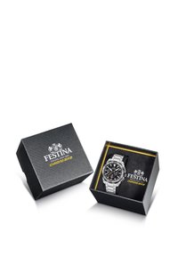 Orologio in acciaio inossidabile argento esposto in una scatola nera con texture e rifiniture dorate. Il quadrante nero presenta accenti bianchi e indicatori luminosi.