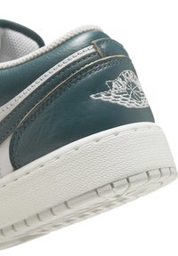 Teal lædersneaker med hvide akcenter, der har en tekstureret sål og broderet design på hælen. Rund form og snørebåndsstil.