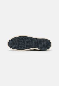 Rubber sneaker sole in dark blue with a textured crosshatch pattern. Features a cream-colored edge and rounded heel for stability.