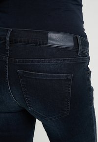 Mörkblå denimjeans med en slät yta, en subtil glans, en bakficka med en dekorativ söm och en märkesläderetikett.
