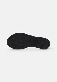 Black shoe sole with textured grip pattern, brand logo embossed, and smooth edges. Material appears rubber with a matte finish.
