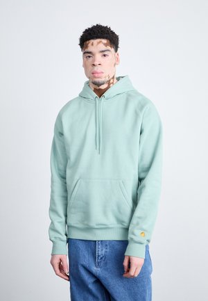 Lys grøn sweatshirt med hætte, kengurulomme og elastiske manchetter. Fremstillet af blødt stof, som har en lille gul logo detalje på ærmet.