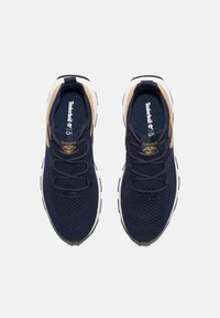 Zapatillas deportivas de malla marinas con acentos beiges. Las características incluyen cordones redondos, diseño transpirable, cuello acolchado y suela de goma con tracción.