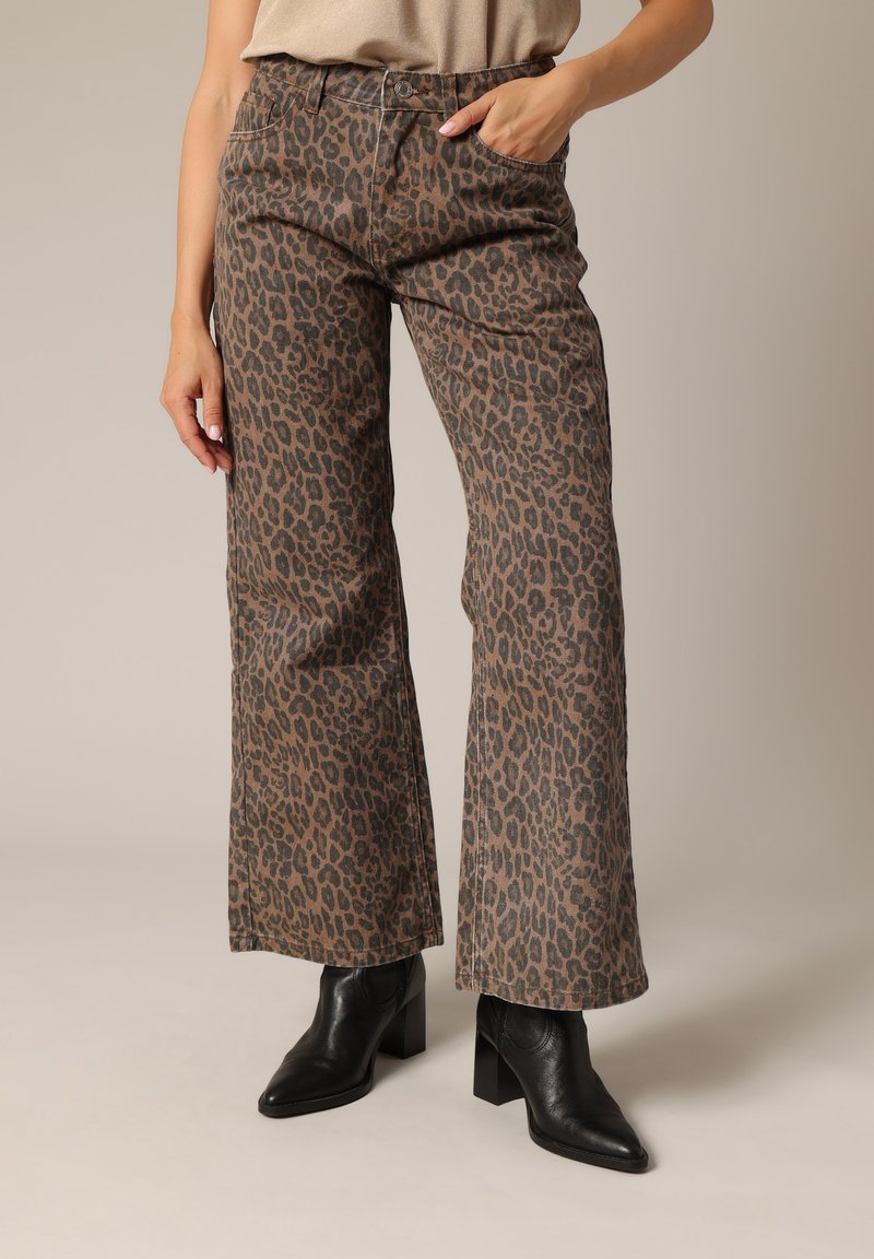 Pantalons à larges jambes en imprimé léopard marron et noir, en tissu doux, dotés de deux poches latérales et d'une taille haute. Stylés avec des bottines noires.