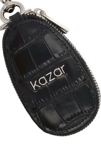 Čierny kožený kľúčový obal s krokoďlím vzorom a strieborným zipsom. Obsahuje strieborné logo "Kazar". Hladká textúra s lesklým povrchom.